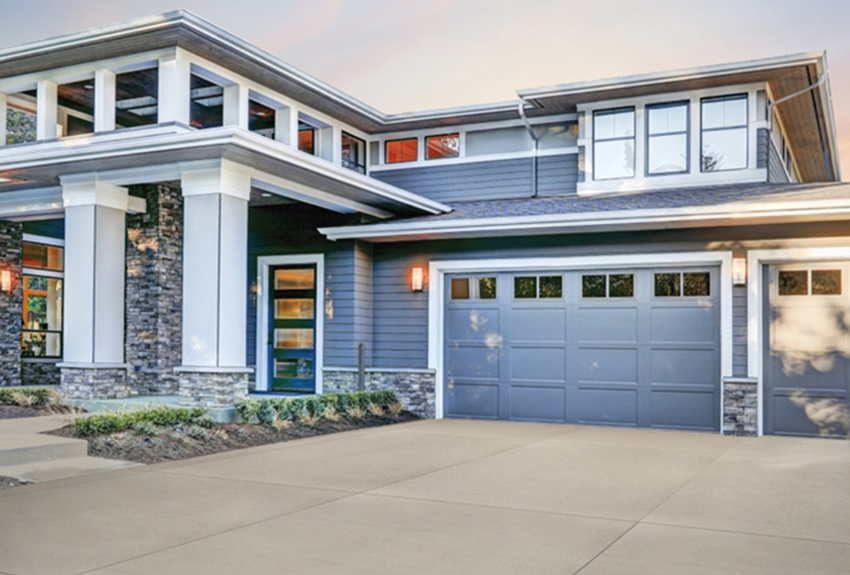 Modern 2-story home with blue garage doors and siding, squared, stone-base columns, and large white windows.