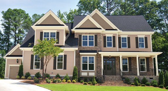 Large home with brick and Hopsack exterior, Universal Umber peaked roofs and Ivory Lace trim. Well-manicured lawn.