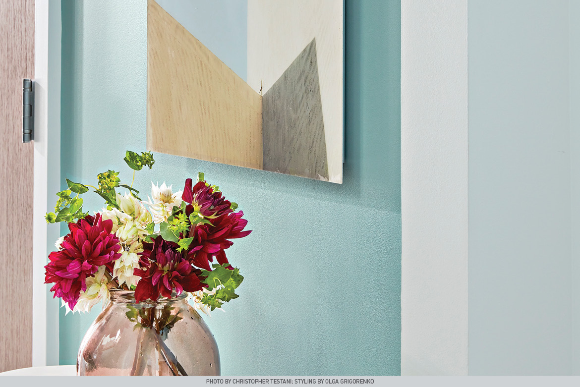 Renew Blue welcomes in the entryway and creates a cheerful anchor for modern art and bouquet of flowers.